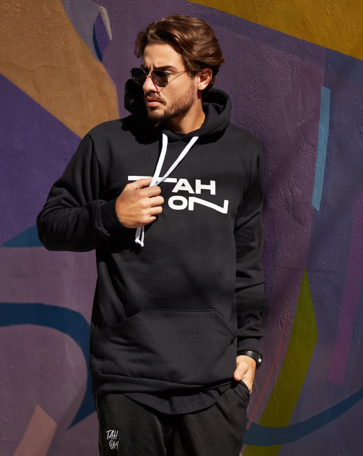 Moletom hoodie preto TAH ON com logo branco no peito, em editorial de rua